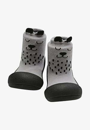 Calcetines grises con una suela de goma negra. Presentan un diseño juguetón de la cara de un perro con orejas negras y acentos de puntos en el cuerpo.