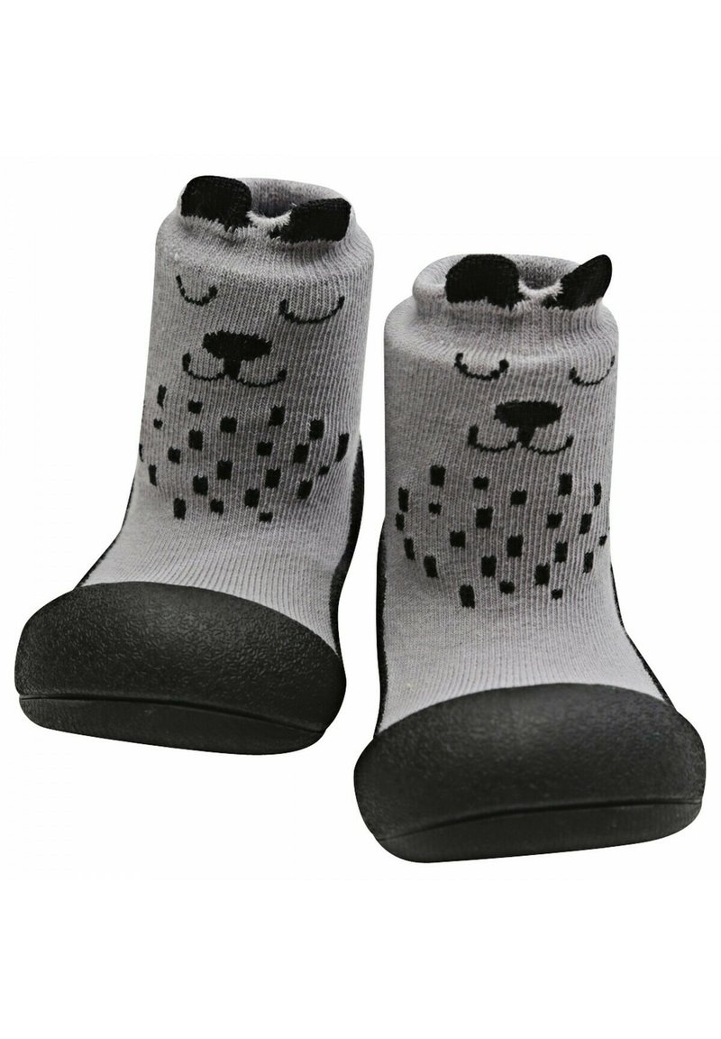 Calcetines grises con una suela de goma negra. Presentan un diseño juguetón de la cara de un perro con orejas negras y acentos de puntos en el cuerpo.