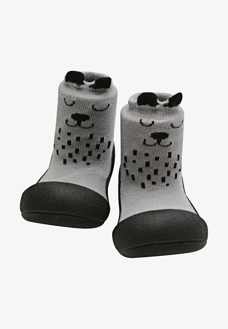 Calcetines grises con una suela de goma negra. Presentan un diseño juguetón de la cara de un perro con orejas negras y acentos de puntos en el cuerpo.