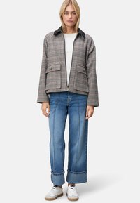 Kurtka w kratę z czarnym kołnierzem i dwoma przednimi kieszeniami, zestawiona z szerokimi niebieskimi dżinsami i białymi trampkami. Regularny krój.