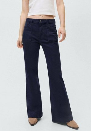 Marinblå utsvängda jeans i denim med framfickor och knappstängning. Slät textur med en klassisk design.