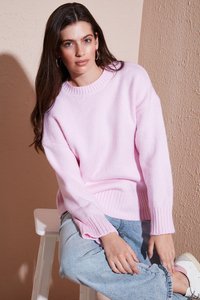 Helle rosa gestrickte Sweater mit einem gerippten Kragen und Bündchen. Kombiniert mit blauen Jeans und weißen Sneakers. Weiche Textur und lockere Passform.