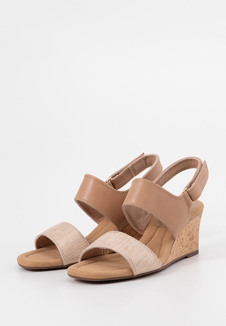 Sandalias de cuña en color beige con parte superior de cuero suave, tira de tela texturizada en beige y tacón de corcho. Correa trasera ajustable para un ajuste seguro.