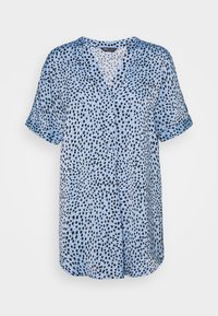 Blusa azzurra chiara a maniche corte con motivo a macchie nere, scollatura a V e chiusura con bottoni, realizzata in tessuto liscio e leggero.