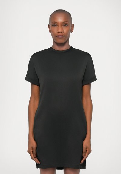 Robe noire à manches courtes avec un col rond, texture lisse et forme évasée, présentant des poignets roulés et un détail de couture subtil.