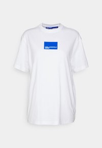 Hvid bomulds t-shirt med et blåt rektangulært logo på brystet, der står "KARL LAGERFELD JEANS." T-shirten har korte ærmer og en rund hals. 