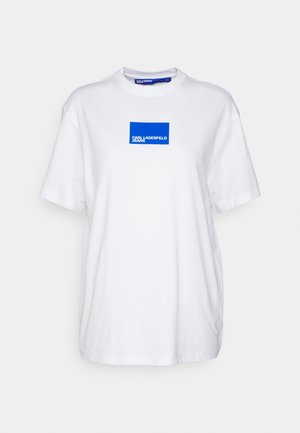 Bijela pamučna majica s plavim pravokutnim logotipom na prsima s natpisom "KARL LAGERFELD JEANS." Kratki rukavi i okrugli izrez.