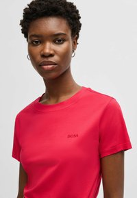 T-shirt rosso a maniche corte realizzato in tessuto morbido, con un piccolo logo "BOSS" in rilievo sul petto.