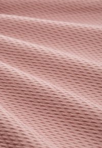 Měkká růžová texturovaná tkanina s vzorem včelí plástve, skládající se s viditelnými záhyby a hladkým povrchem, ideální pro čalounění nebo oblečení.