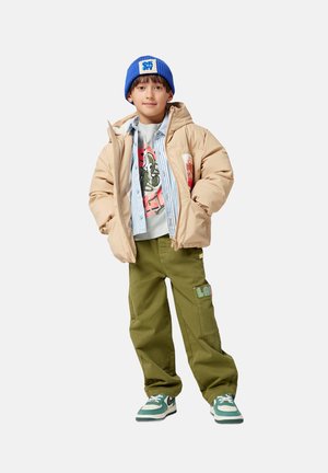 Beżowa kurtka puchowa, niebieska dzianinowa czapka, szary T-shirt z grafiką, pasiaste koszula, zielone spodnie cargo i zielono-białe sneakersy.