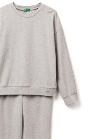 Sudadera gris hecha de un tejido suave, con cuello redondo y hombros caídos. Incluye una pequeña etiqueta con el logo cerca del dobladillo.