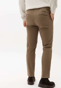 Slim-fit bruine geruite broek met twee achterzakken, subtiele textuur en een recht gesneden ontwerp; gecombineerd met donkere suède enkelboots.