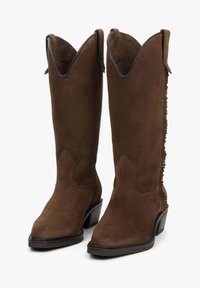 Hnědé semišové kovbojské boty s špičatou špičkou, zvlněným vrškem a texturovanou zadní částí s vertikálními třásněmi. Pevný blokový podpatek.