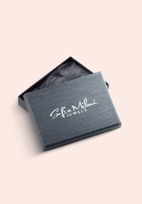 Grå smykkeskrin med tekstureret finish, med en hvid logo "Sofia Milani JEWELS." Skrinet er delvist åbent og afslører sort silkepapir indeni.