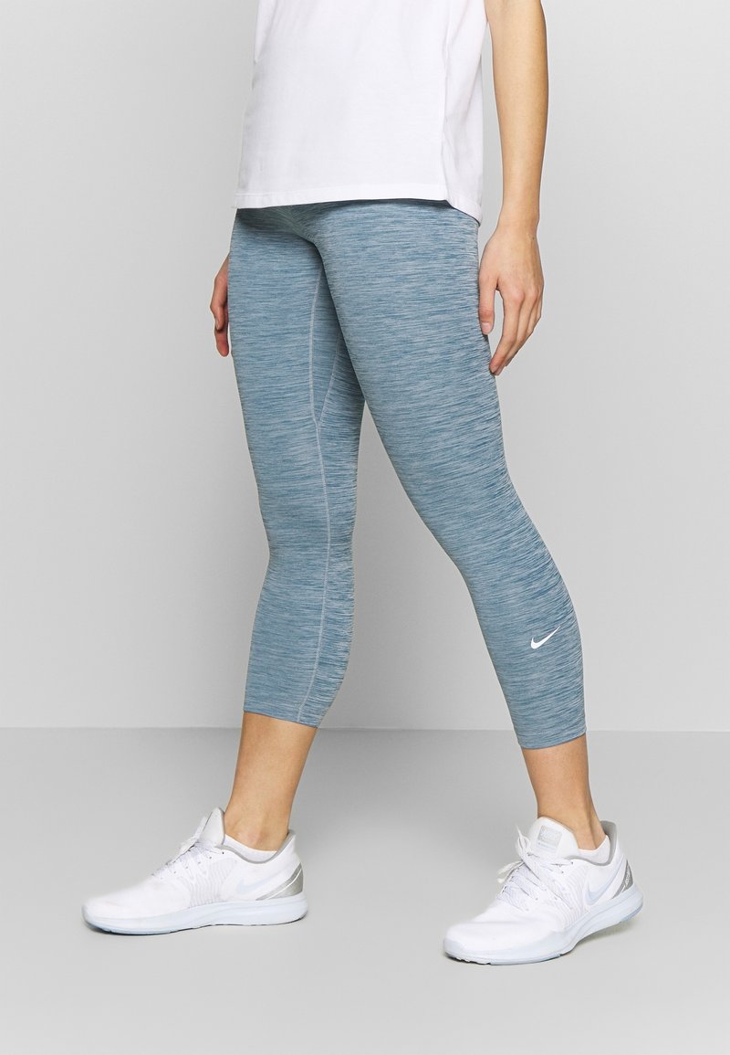 Jasnoniebieskie legginsy sportowe o teksturowanym wykończeniu, z dopasowanym krojem i długością do kolan. Połączone z białymi butami Nike.