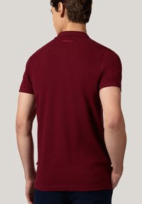 Bordowa koszulka polo z krótkim rękawem i klasycznym kołnierzykiem, z delikatnym logo z tyłu i gładką, miękką teksturą.