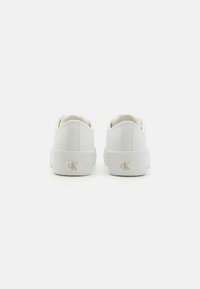 Hvite sneakers laget av glatt syntetisk materiale, med avrundet tå, lavt design og subtil logo detaj på hælen.
