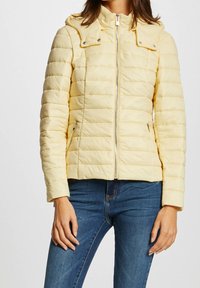 Yellow padded jacket with a zip closure, featuring a hood and snap button accents. The texture is smooth with horizontal stitching details.
