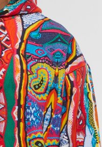 Helle farbige Kapuzenjacke mit komplexen geometrischen und abstrakten Mustern in Rot, Gelb, Blau und Grün, die das gestickte "Colcci"-Logo zeigt.