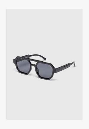 Black geometric-frame sunglasses with dark tinted lenses and a straight double bridge resting on a light gray surface.