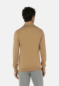Herren Langarm-Polo aus beigem Strickstoff. Verfügt über einen Kragen, gerippte Bündchen und einen geraden Saum. Die Rückansicht zeigt eine glatte Textur ohne Muster.