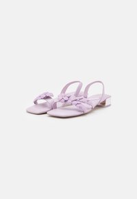 Sandales lilas à bout ouvert avec une texture lisse, ornées de motifs floraux et d'un petit talon bloc. Straps ajustables pour un bon maintien.