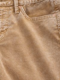 Tan corduroy fabric with fine ribbed texture, featuring a front pocket and visible stitching. Copper hardware accents near pocket.