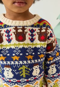 Maglione lavorato a maglia con base blu e motivi multicolori di renne, pupazzi di neve, alberi e stelle. Scollo a coste color crema.