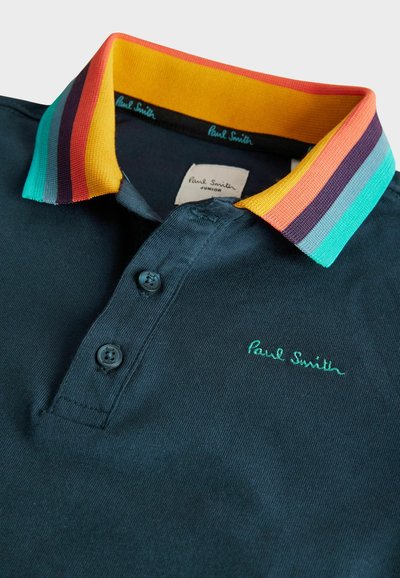 Námornícká polo košeľa s rebrovaným farebným golierom; obsahuje gombíky a vyšívané logo "Paul Smith" v zelenej farbe. Mäkká bavlnená textúra.