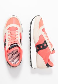 Laufschuhe mit einem Obermaterial aus beigem Wildleder und korallenfarbener Netzstruktur, schwarzen Akzenten und einer weißen Mittelsohle. Ausgestattet mit strukturierten Schnürsenkeln und einem gemusterten Fußbett.