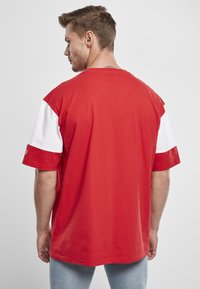 Rood en wit T-shirt met korte mouwen, met een ronde hals, een relaxte pasvorm en contrasterende stof op de mouwen met een gladde textuur.