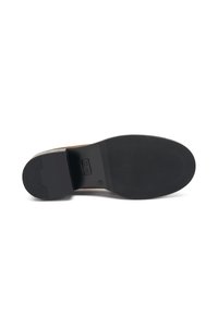 Sole di scarpa in pelle marrone con un distintivo fondo in gomma nera testurizzata. Presenta un leggero tacco e un logo impresso al centro.