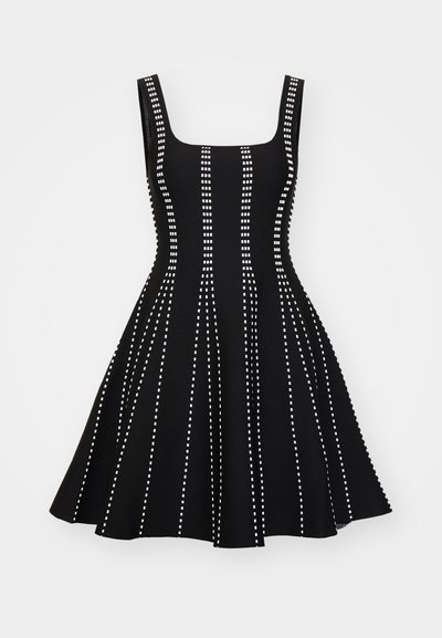 Robe ajustée sans manches noire avec un col carré, présentant des lignes blanches verticales en pointillés et une jupe évasée.