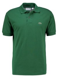 Polo vert en coton texturé, avec un col classique, une patte de boutonnage à deux boutons, et un logo brodé sur la poitrine gauche.