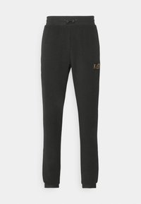 Svarta joggerbyxor i texturerad tyg med dragsko i midjan. Har en liten gul logotyp vid höften och ribbade muddarna vid anklarna.