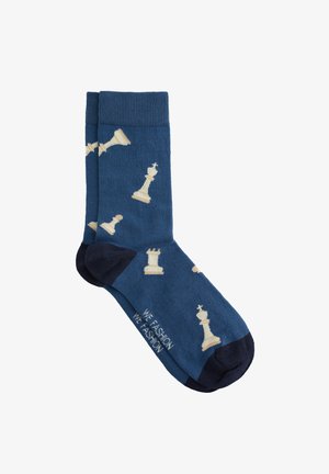 Blaue Socken mit cremefarbenen Schachfiguren-Mustern, dazu ein marineblauer Akzent an der Zehenpartie und ein geripptes Bündchen. Hergestellt aus weichem, strukturiertem Material.