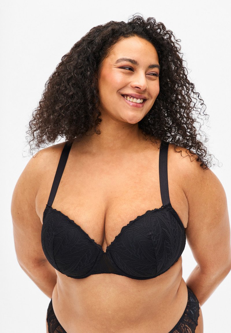 Black lace bra with molded cups, scalloped edges, and adjustable straps. The fabric features a floral pattern and soft texture.