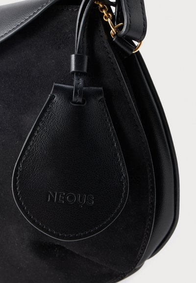 Μαύρη δερμάτινη τσάντα χειρός από δέρμα και σουέντ με δερμάτινη ετικέτα σε σχήμα σταγόνας, που φέρει ανάγλυφο το λογότυπο "NEOUS", προσαρτημένη με δερμάτινο λουρί και χρυσή αλυσίδα.