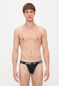 Schwarze Nike-Damenslip mit weißem, gebrandetem Taillenbund, der eine glatte Textur und ein figurnahes Design bietet.