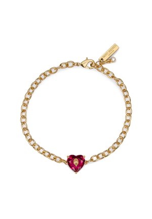 Gouden kettingarmband met een hartvormige donkerroze edelsteen in het midden. Voorzien van een karabijnsluiting en een merkembleem met een kleine, heldere accentsteen.