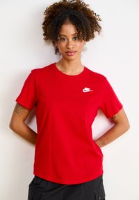 Tricou din bumbac roșu, cu guler rotund și mâneci scurte. Un logo alb Nike este plasat pe partea stângă a pieptului. Textură netedă, croială lejeră.