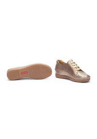 Zapatillas metálicas doradas con parte superior perforada, diseño de cordones y suela acolchada. Patrones texturizados detallados en la suela. Tacón en cuña.