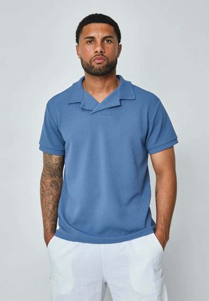 Polo à manches courtes en bleu clair, en tissu texturé, avec un design de col replié unique et une coupe décontractée.