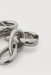 Κοντινή λήψη από λαμπερούς, διασυνδεδεμένους συνδέσμους αλυσίδας από ασημί μέταλλο σε απλό λευκό φόντο.