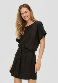 Robe en lin noir avec des manches courtes, une coupe décontractée, une taille cintrée, des détails de ceinture et des poches latérales. Le tissu a une texture lisse.