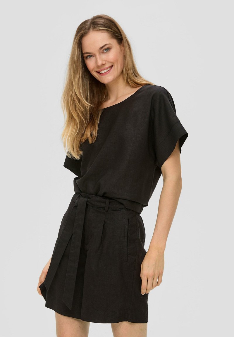 Robe en lin noir avec des manches courtes, une coupe décontractée, une taille cintrée, des détails de ceinture et des poches latérales. Le tissu a une texture lisse.