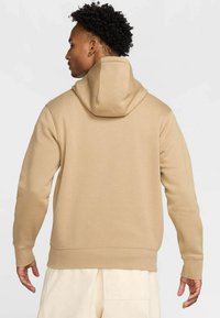 Felpa beige con cappuccio regolabile, texture morbida e polsini a coste. Il retro presenta un design senza cuciture, che enfatizza una vestibilità rilassata.