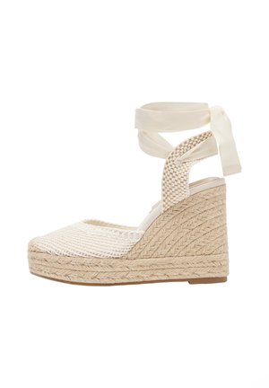 Beige kileespadrille med flettet juteplatform, lukket mesh-tå og bånd til at binde om anklen.