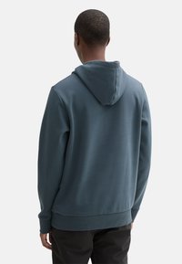 Felpa con cappuccio di un blu tenue; realizzata in tessuto morbido con una vestibilità comoda, polsini a coste e una tasca a marsupio.