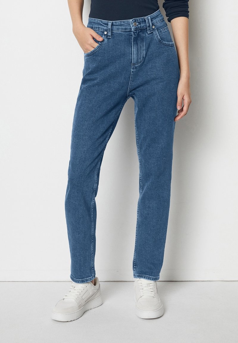 Jeans i denim med en medelblå tvätt, hög midja, rak passform, med framfickor och subtila sömnadsdetaljer. Bärs med vita sneakers.